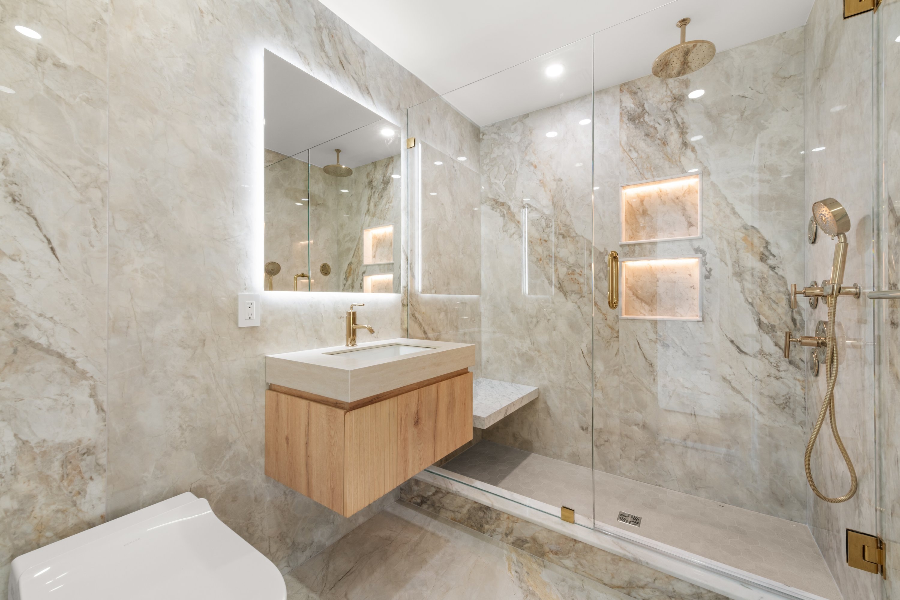 Modern bathroom renovation with floating vanity and backlit mirror